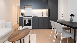 Una cocina moderna con armarios oscuros, estufa, microondas y comedor con mesa y sillas.
