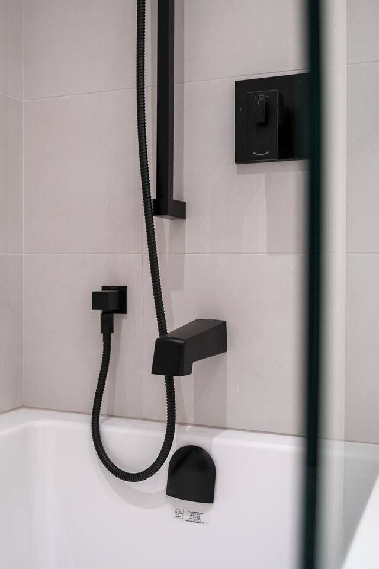A modern shower with a handheld hose and a wall-mounted control panel.