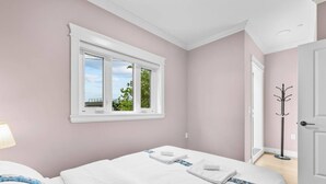 Een slaapkamer met een bed, een raam met uitzicht en een kapstok.