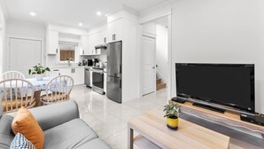 Een moderne keuken met witte kasten, een roestvrijstalen koelkast en een eethoek met een tafel en stoelen.