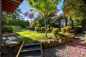 Ein Garten mit einem Kiesweg, einem kleinen Baum und einer Holzterrasse.