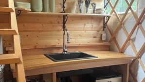 Un angolo cottura funzionale con lavandino, scaffali in legno e frigorifero.