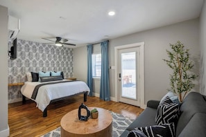 A bedroom with a bed, a ceiling fan, a window with curtains, a plant, and a view of the outside. - Private gated studio with parking, fast WiFi, and easy self check-in minutes from Downtown Houston and attractions (Houston)