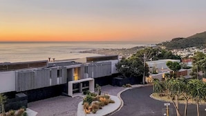 A modern building with a view of the ocean at sunset. - Room-private Luxury Winter Escape Design (Cape Town)