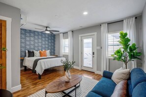 Ein modernes Schlafzimmer mit einem Bett, einem Deckenventilator und einem großen Fenster.