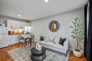 A modern living room with a sofa, coffee table, and dining area. - Comfortable Houston hideaway near Downtown and attractions with fast WiFi, parking (Houston)