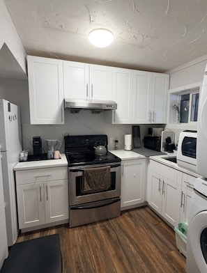A modern kitchen with white cabinets, stainless steel appliances, and a wooden floor. - Cozy 2BR Suite · Near Crescent Beach & Trails (Surrey)