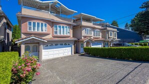 Un immeuble résidentiel à plusieurs étages, doté d’un garage, d’un balcon et d’une allée bien entretenue.