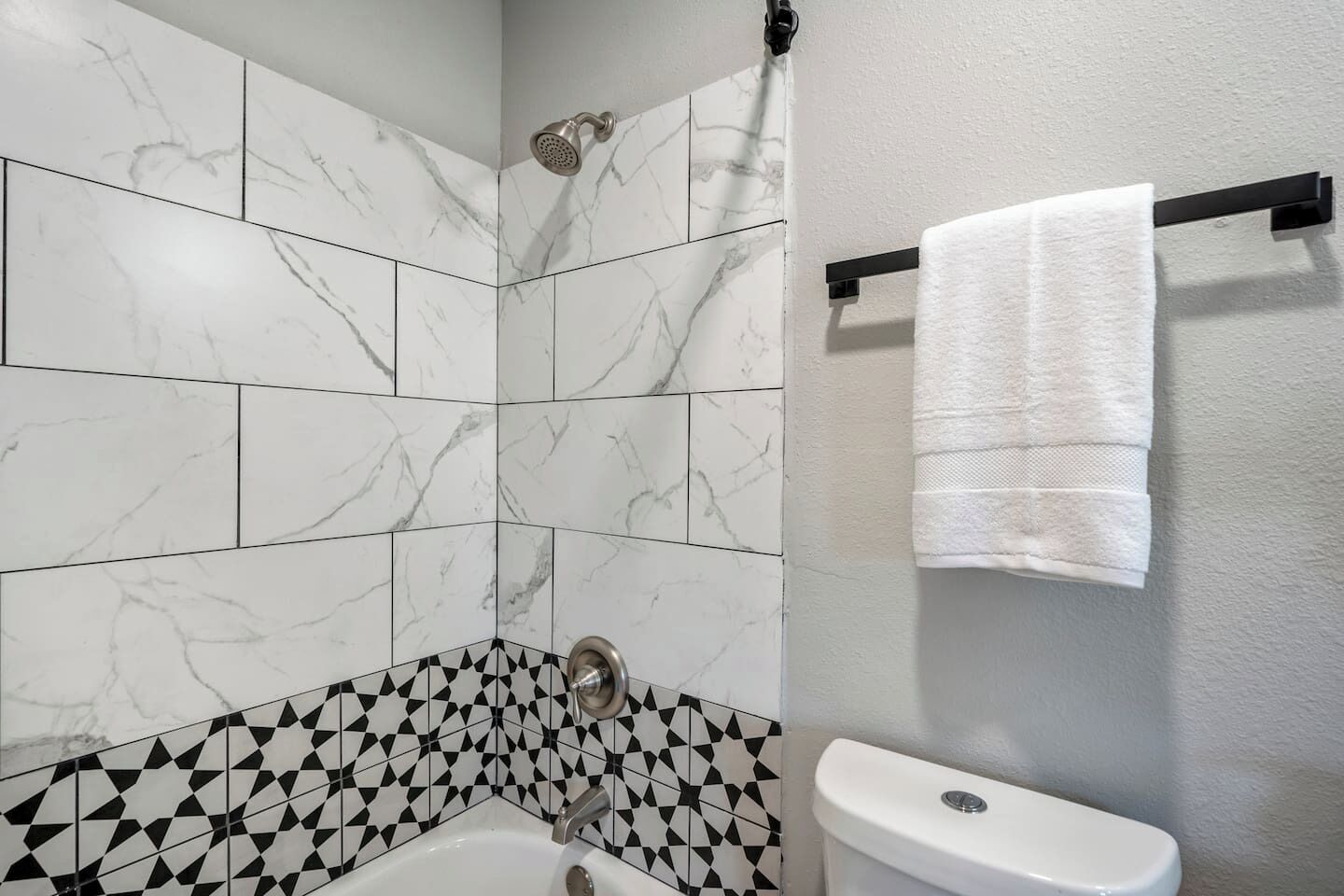 A bathroom with a shower, a toilet, and a towel rack.