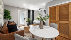 Un salon moderne avec une table ronde, un canapé, une table basse et une porte donnant sur une chambre à coucher.