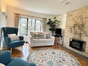 A living room with a sofa, armchair, and a fireplace. - Alma Cottage - 3 minute walk to Studland beach, garden, parking 3 bedrooms (Studland)