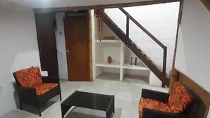 Une pièce avec deux canapés, une table basse, une porte en bois et un escalier.