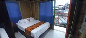 Un letto singolo in una stanza con vista sugli edifici attraverso una finestra.
