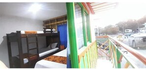 Una habitación con literas, ventana con vista a la calle y balcón con barandillas.