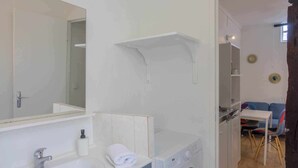 A compact bathroom with a sink, mirror, and a washing machine. - Small studio downtown (Orléans)
