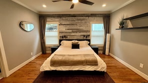 A bedroom with a bed, bedside tables, a ceiling fan, and a wooden accent wall. - Luxe Modern Farmhouse in the heart of everything! (Atlanta)