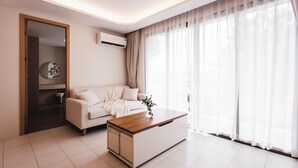 Ein stilvolles Wohnzimmer mit einer Couch, einem Couchtisch und durchsichtigen Vorhängen.
