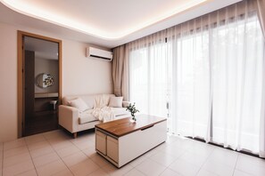 Ein stilvolles Wohnzimmer mit einer Couch, einem Couchtisch und durchsichtigen Vorhängen.
