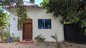 A house with a wooden door, a window, and a black gate. - Zan Culinary (W7F2+VM Zanzibar, Tanzania)