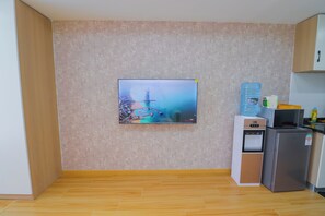 Eine moderne Küche mit einem flachbildfernseher an der Wand, einem Wasserspender und einem Kühlschrank.