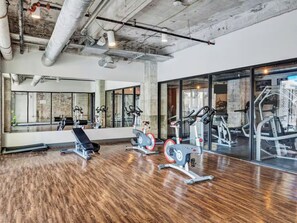 Ein Fitnessstudio mit Trainingsgeräten, Holzboden und großen Spiegeln.