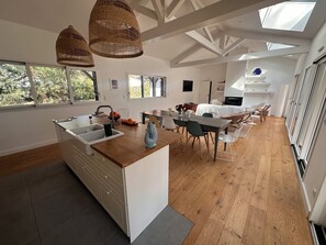 A modern kitchen with a central island, wooden flooring, and large windows. - Villa The Burrow - a stone's throw from Lake HOSSEGOR (HOSSEGOR)