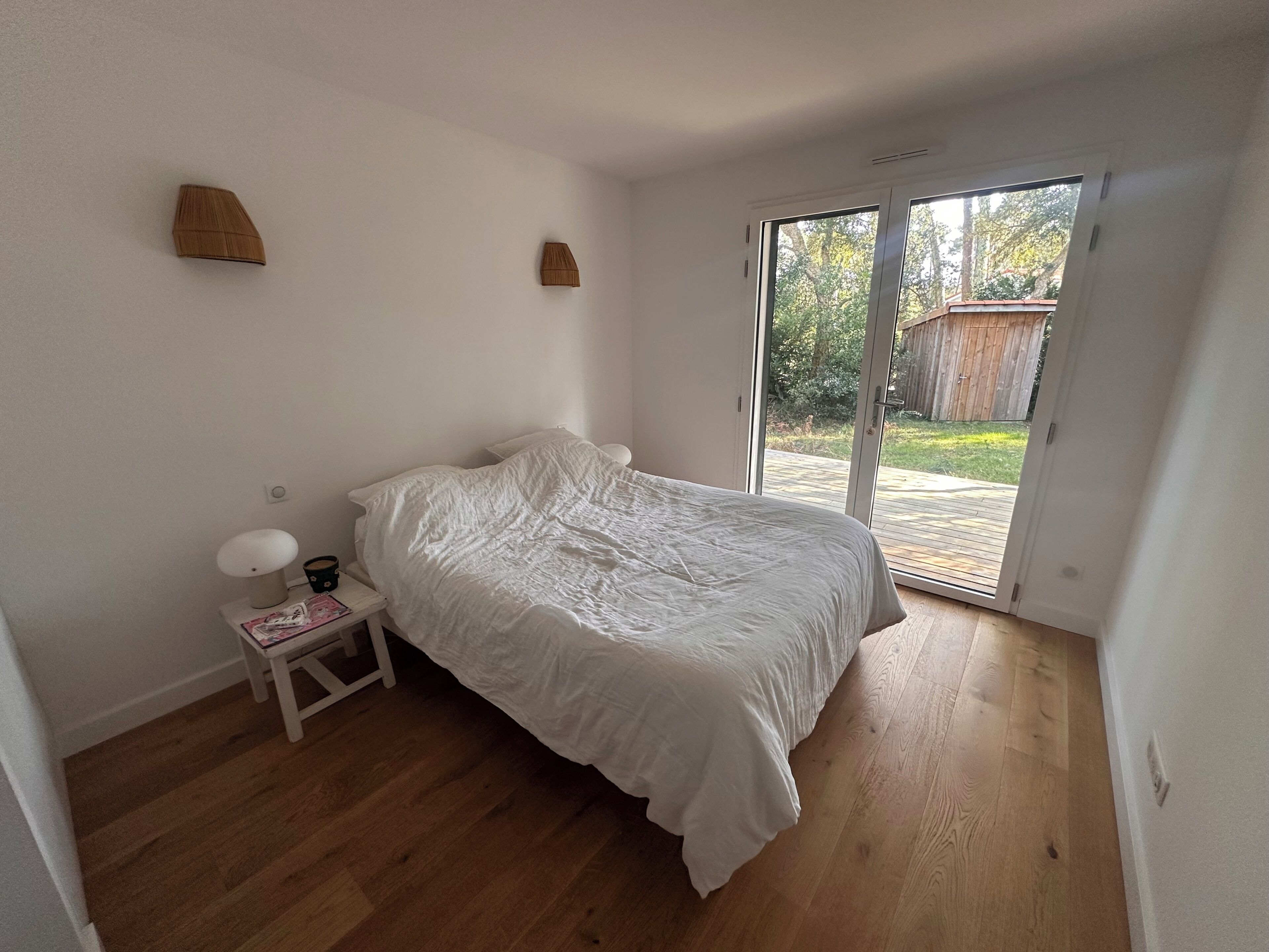 A bedroom with a bed, a nightstand, a lamp, and a sliding glass door leading to an outdoor area.