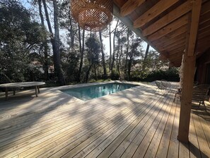A wooden deck with a swimming pool, surrounded by trees. - Villa The Burrow - a stone's throw from Lake HOSSEGOR (HOSSEGOR)