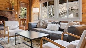 A cozy living room with a fireplace, a sofa, a coffee table, and a view of the outside. - Cozy Duplex in West Vail – Near Vail Village (Vail)