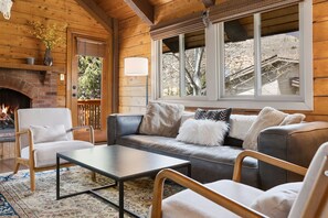 A cozy living room with a fireplace, a sofa, a coffee table, and a view of the outside. - Cozy Duplex in West Vail – Near Vail Village (Vail)