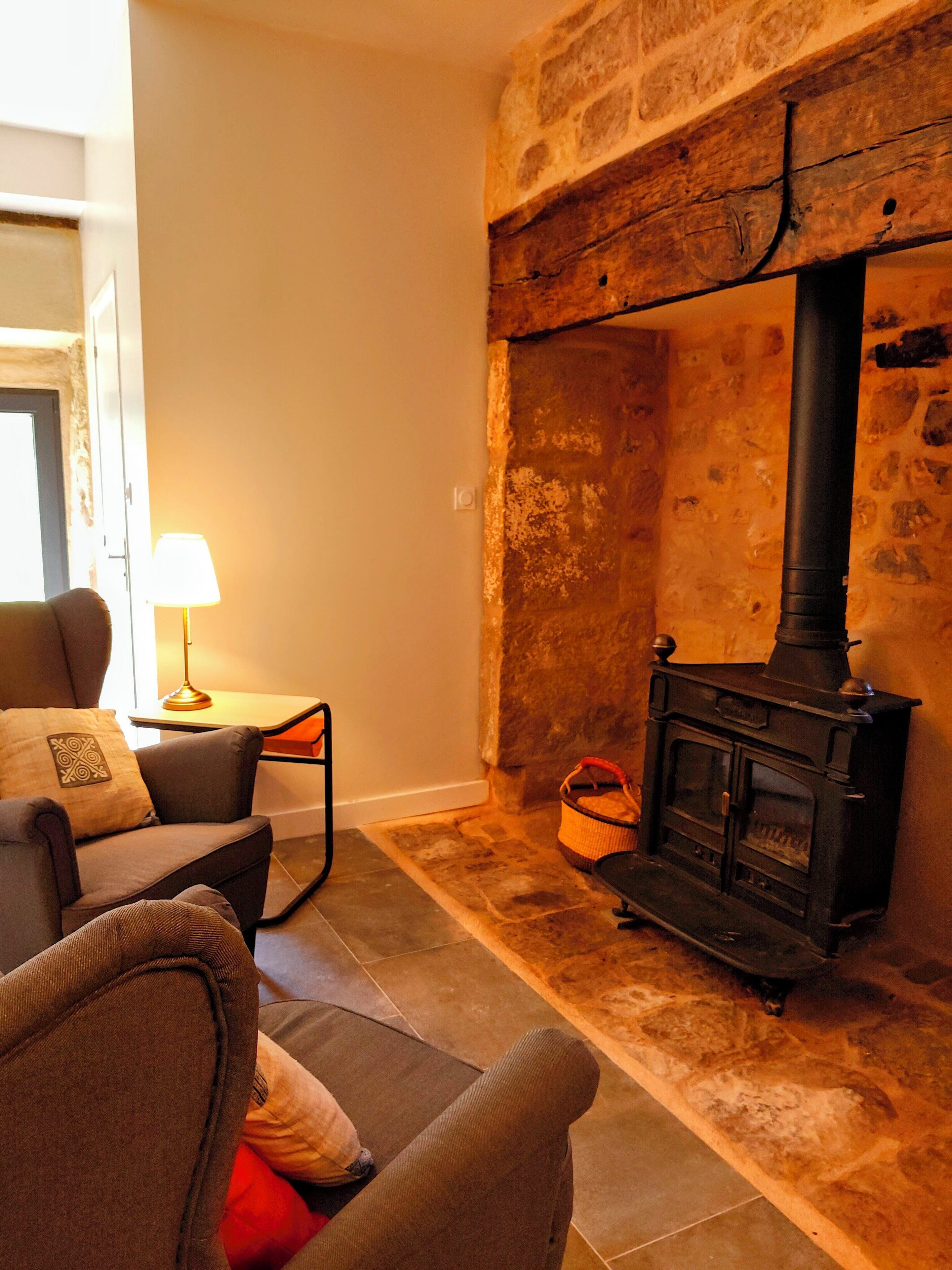 A cozy living room with a stone fireplace, a sofa, a lamp, and a small table.