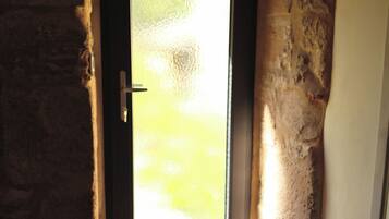 Une porte dotée d’un panneau en verre dépoli, d’une poignée de porte et d’un mur en pierre situé à côté.