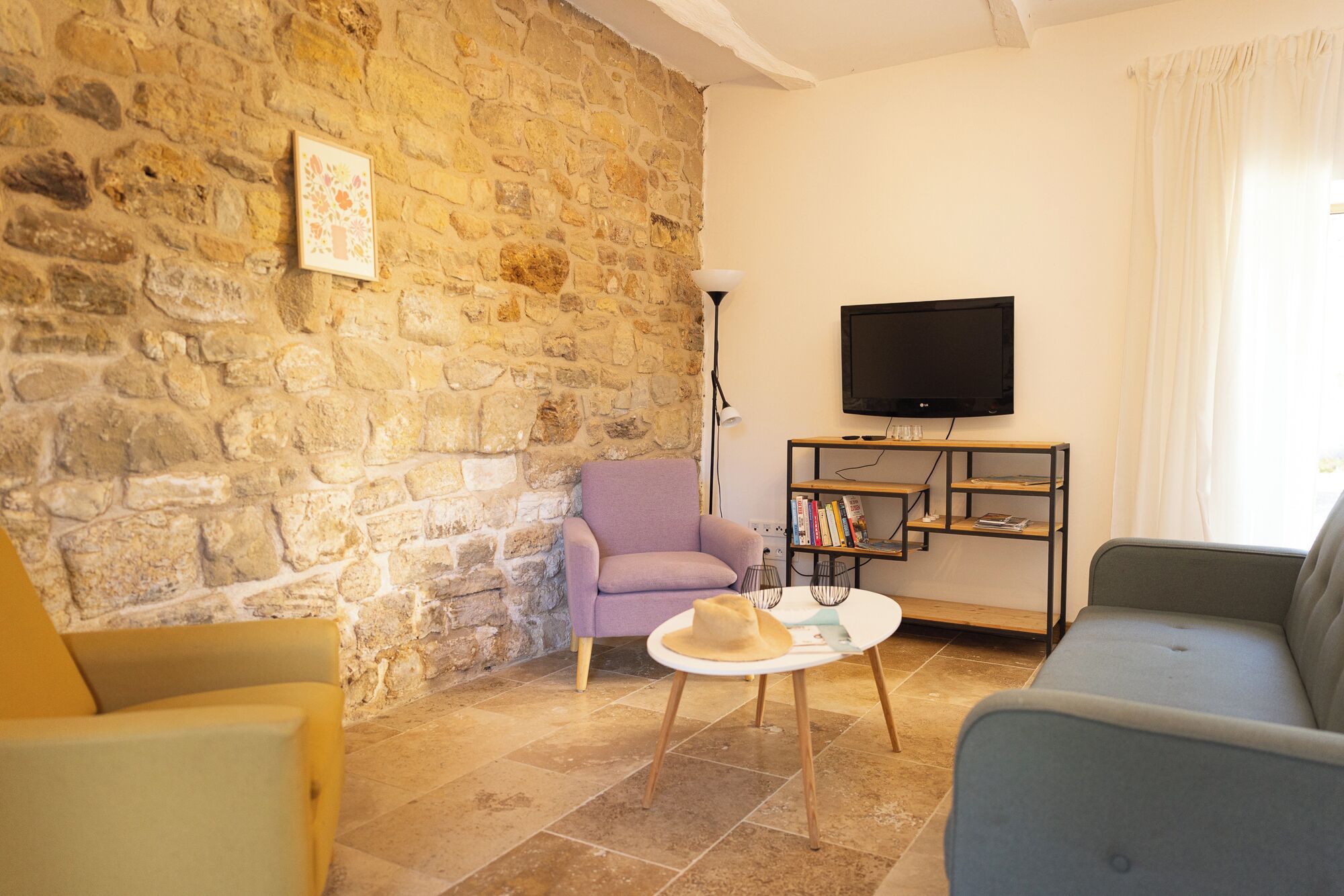 A living room with stone walls, a television, a bookshelf, and two sofas.