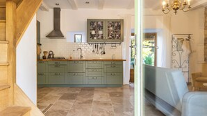 A kitchen with green cabinets, a stove, and a hanging utensil rack. - Le Mas d'Ayen (Ayen)