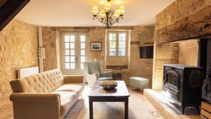 A cozy living room with a fireplace, a sofa, a table, and a chair. - Le Mas d'Ayen (Ayen)