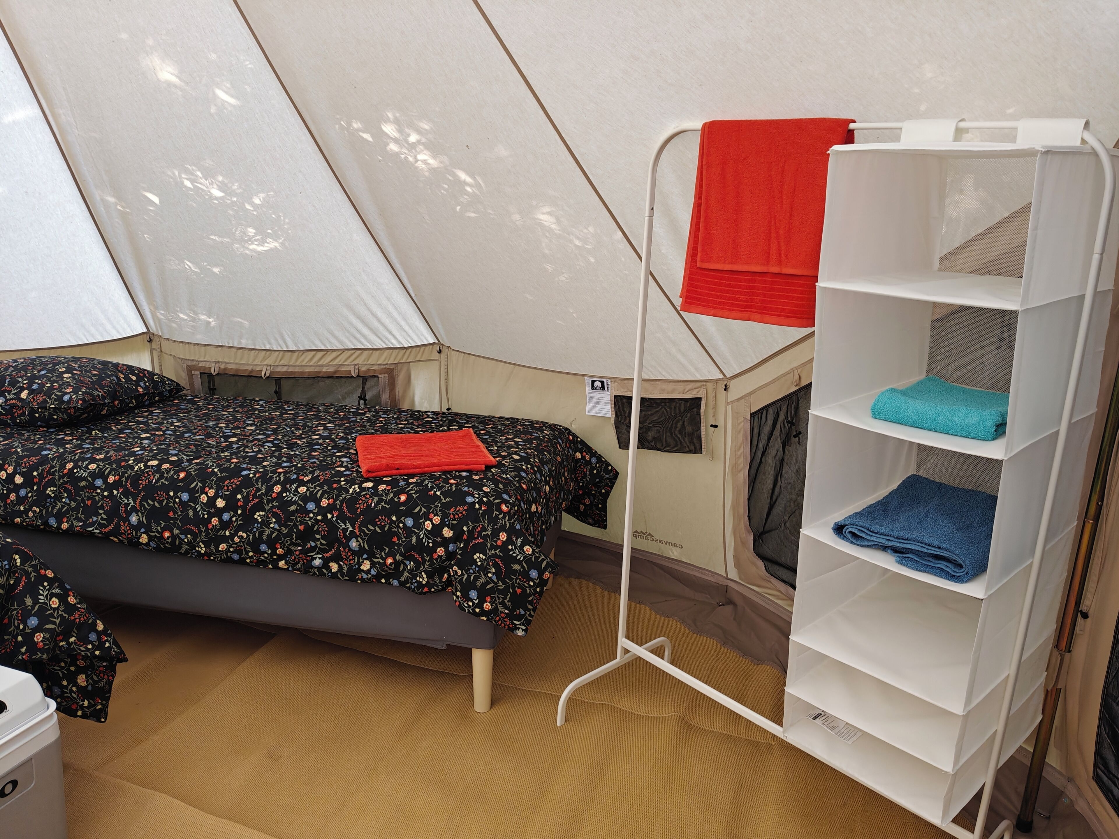 Una habitació amb telt, un llit, una estant i un matalàs a terra.