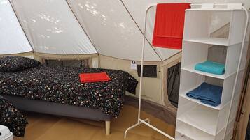 Una habitació amb telt, un llit, una estant i un matalàs a terra.