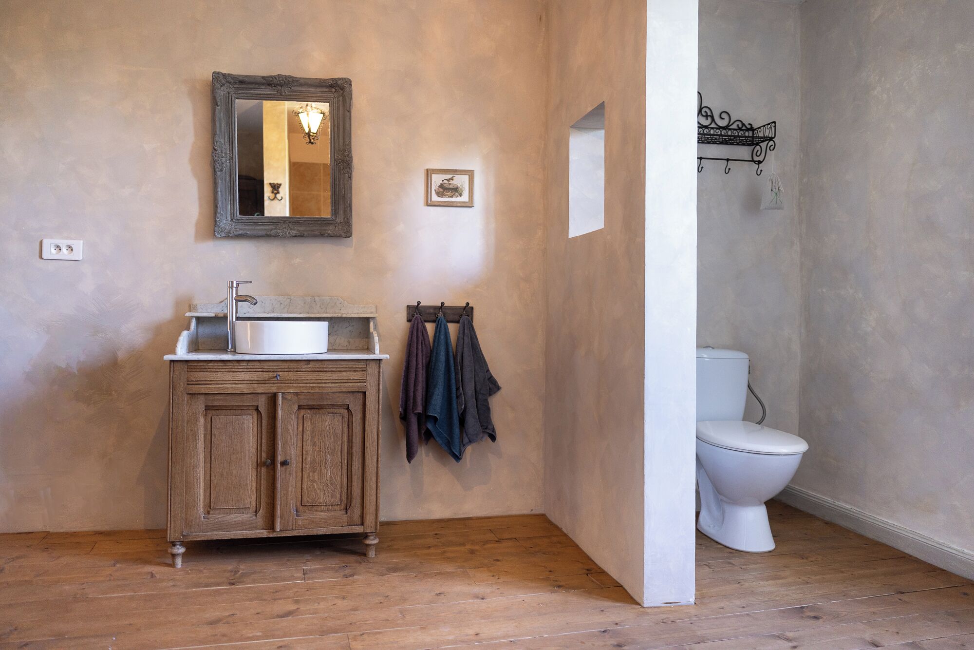 A bathroom with a wooden cabinet, a sink, a mirror, a toilet, and a towel rack.