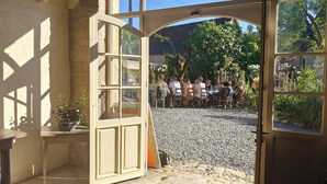 An open doorway leading to a gravel patio with a group of people dining. - Le Mas d'Ayen (Ayen)