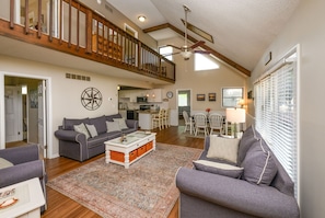 A spacious living area with a high ceiling, a staircase, and a dining area. - Cozy Coastal Cottage in Angola by the Bay (Lewes)