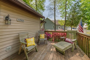 A wooden deck with two chairs and a bench, a house number 33968, and a view of a neighboring house. - Cozy Coastal Cottage in Angola by the Bay (Lewes)