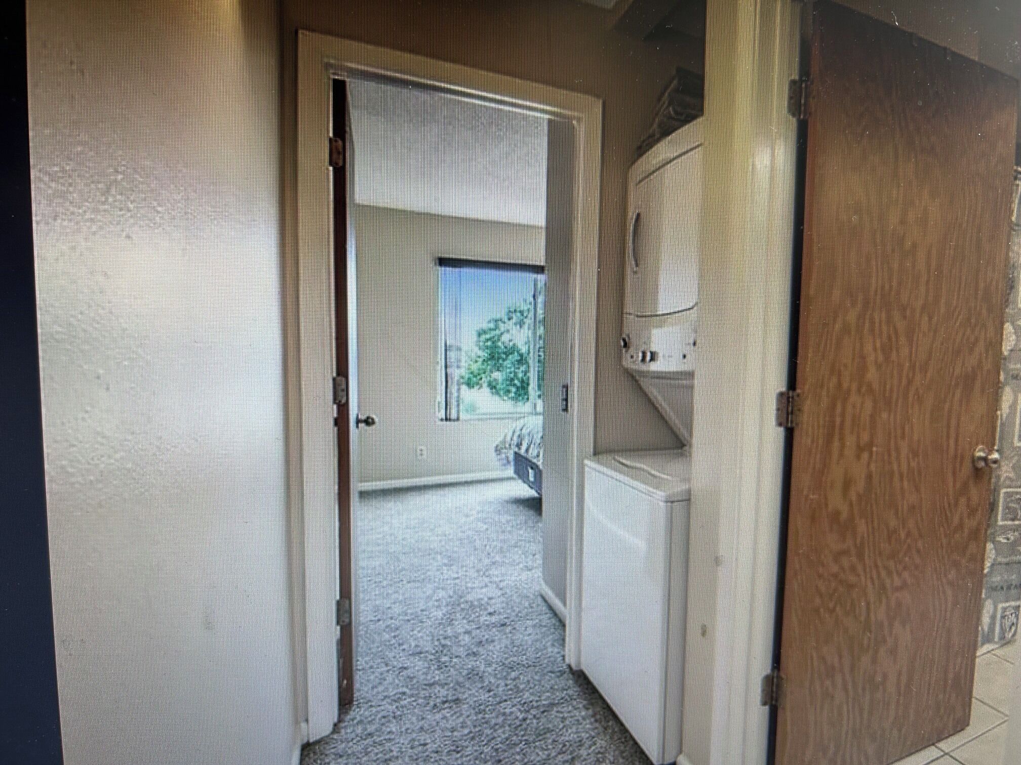 A doorway leading to a room with a visible window and a view of a tree outside.