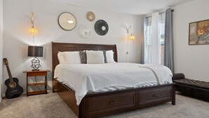 Een slaapkamer met een bed, bedlampen, een gitaar, een kleine tafel en wanddecoraties.