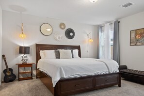 Ein Schlafzimmer mit Bett, Nachttischlampen, einer Gitarre, einem kleinen Tisch und Wanddekorationen.