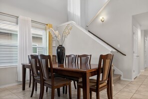 Ein Essbereich mit Holztisch und -stühlen, einer Vase mit Blumen und einer Treppe im Hintergrund.