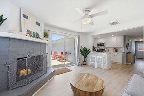 Una sala de estar moderna con chimenea, comedor, cocina y puerta corrediza de vidrio que da a un patio al aire libre.