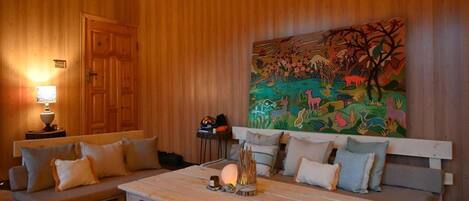 A cozy room with wooden walls, a sofa, a coffee table, and a painting.
