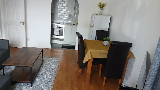 Un soggiorno con divano, tavolino e tavolo da pranzo con sedie. Si intravede una cucina sullo sfondo.