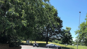 Una strada con un segnale di strada privata, uno scooter parcheggiato e un'auto.