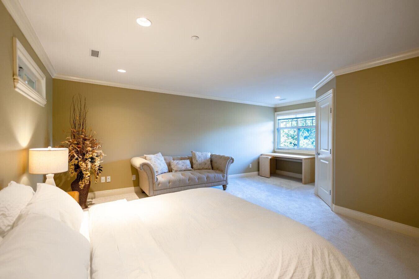 Un dormitorio con cama, sofá, escritorio y ventana.